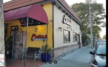 the outside of a restaurant with a yellow facade and a red umbrella